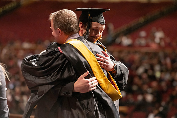 Graduates walk across the stage and accept their diploma.
