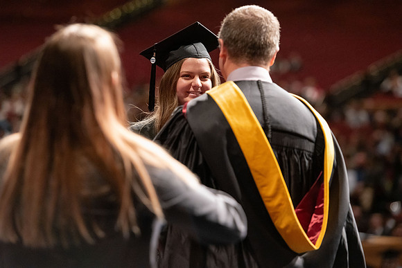 Graduates walk across the stage and accept their diploma.