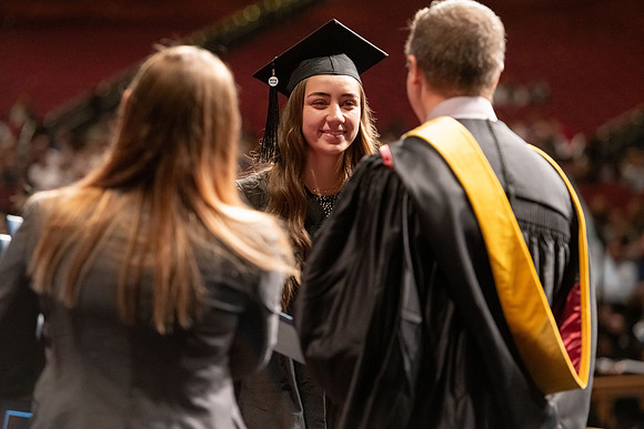 Graduates walk across the stage and accept their diploma.