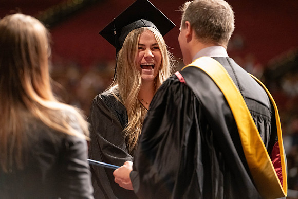 Graduates walk across the stage and accept their diploma.