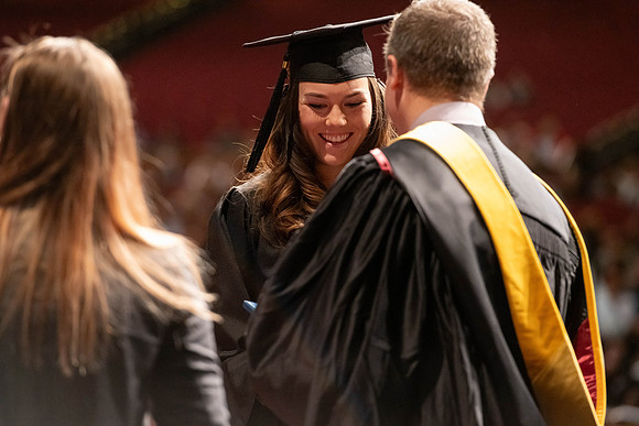 Graduates walk across the stage and accept their diploma.