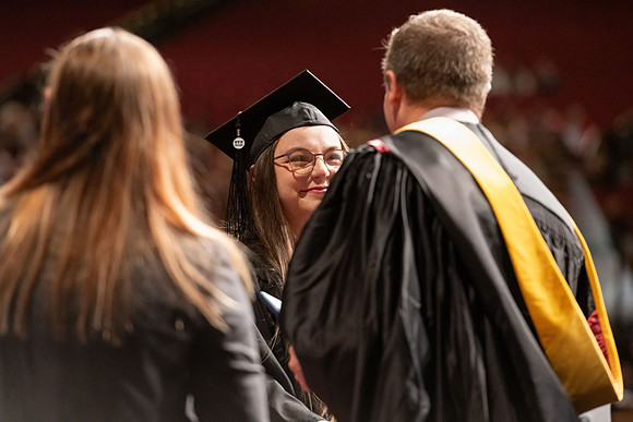 Graduates walk across the stage and accept their diploma.