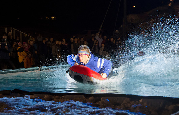 Students make a run down a snowy slope and across a pond of water in the annual event of Pond Skimming.