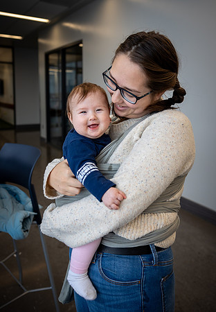 A young student affectionately care for her young baby while preparing for class in the Science and Technology center.