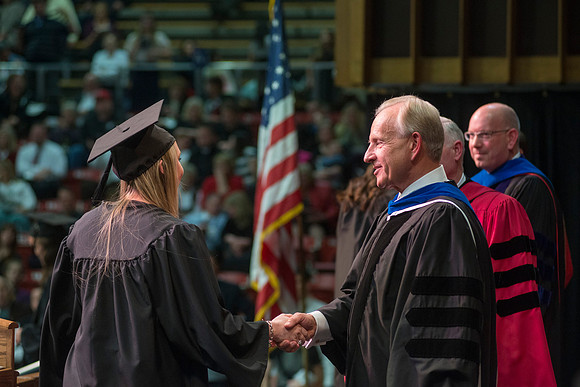 Elder W. Craig Zwick and President Kim B. Clark award diploma covers to graduates in the College of Business and Communication.