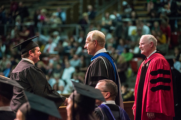 Elder W. Craig Swick and President Kim B. Clark award diploma covers to graduates in the College of Business and Communication.