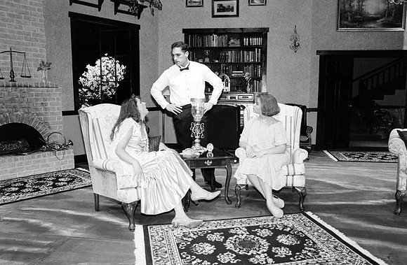 The man has hands on his waist, looking at one of the ladies.