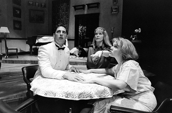 A man and a lady over lapping hands on a table with a spiritualist invoking the spirit.