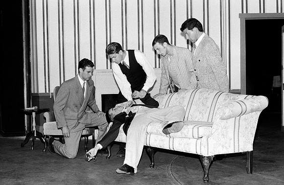 "Ten Little Indians" by Agatha Christie. A man is laying on the coach with people around him.