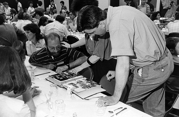 Playmill reunion participants looking at a photo album.
