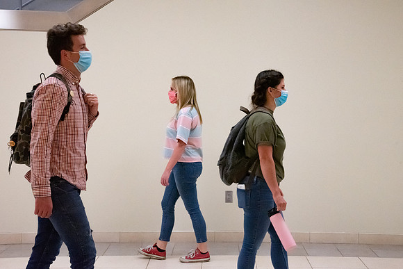Examples of students staying safe and healthy during the COVID-19 pandemic by social distancing, following pathway arrows, and wearing face masks.