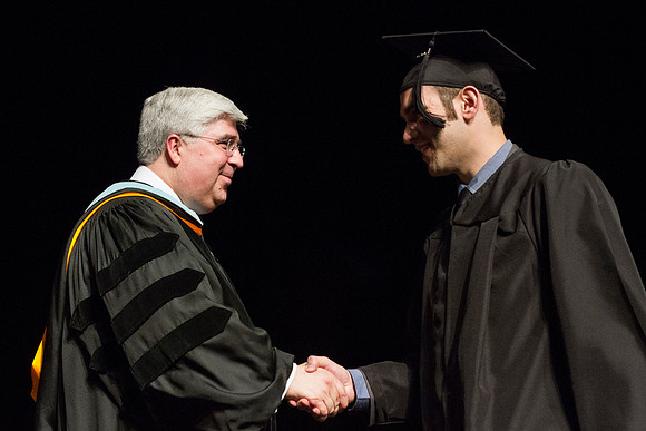 Elder Teixeria of the Europe Area Presidency congratulates a graduate during the Convocation of the College of Business and Communication in the Hart Auditorium.