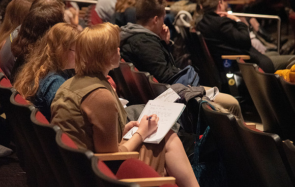 Students taking notes as they listen to devotional in the BYU-Idaho Center. Devotional - Nov 2019