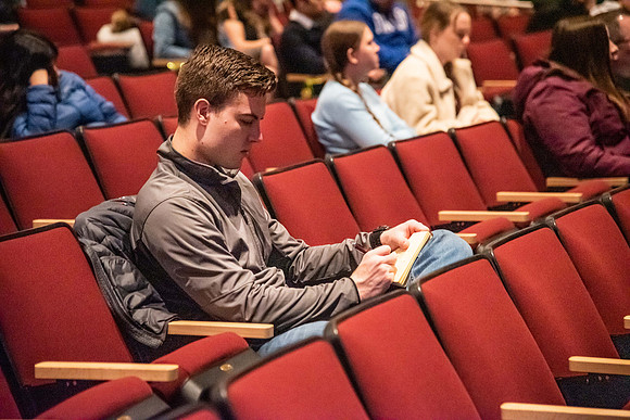 Students taking notes as they listen to devotional in the BYU-Idaho Center. Devotional - Nov 2019