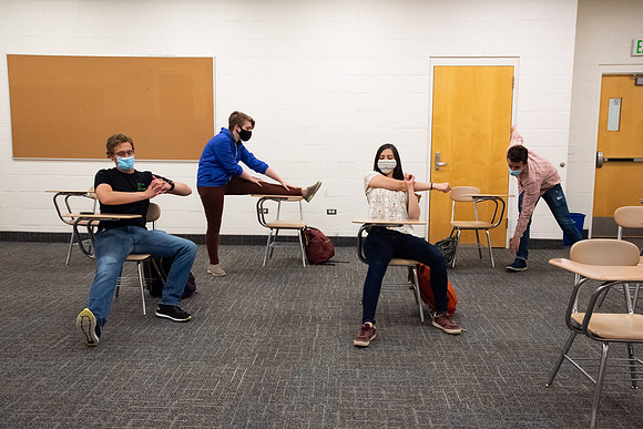 Examples of students staying safe and healthy during the COVID-19 pandemic by social distancing, following pathway arrows, and wearing face masks.