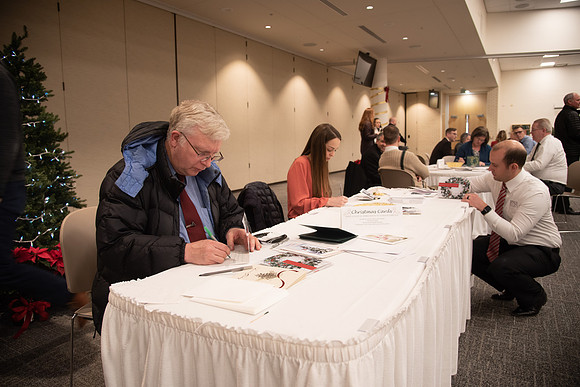 Employees writing a card at the Employee Christmas Pie Social.