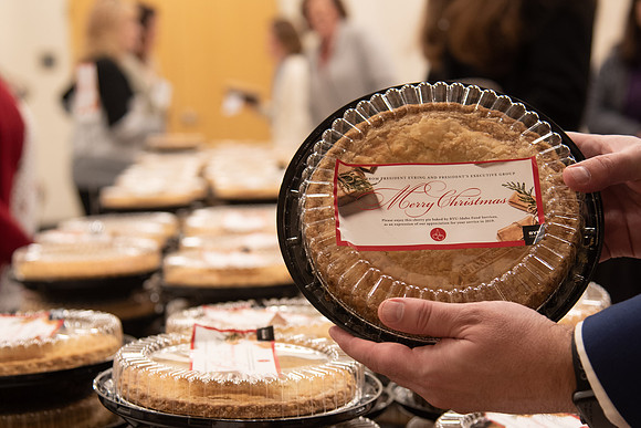 Table of pies for employees to get from President Eyring and President's Executive Group. Employee holding up a pie.