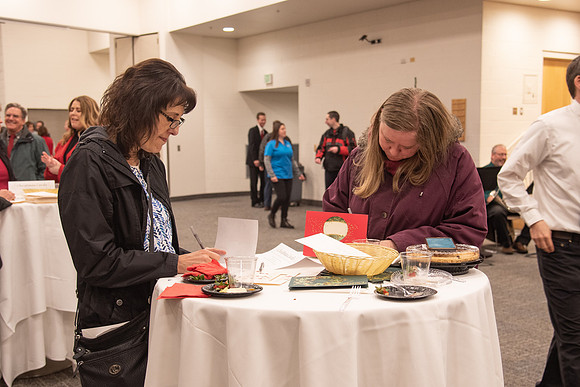 Employees writing a card at the Employee Christmas Pie Social.