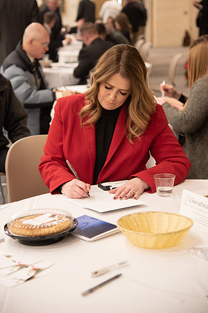 Employee writing a card at the Employee Christmas Pie Social. Vice President Amy LaBaugh