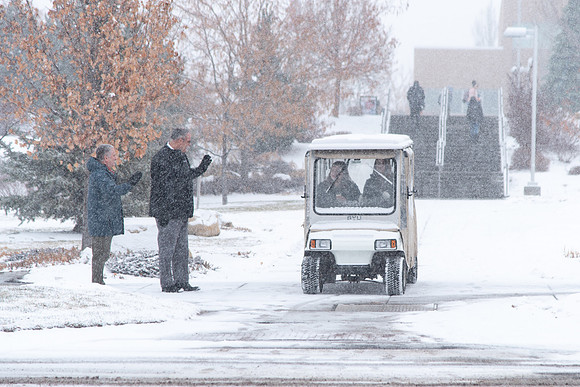 Fresh snow falling on campus of BYU-Idaho. Employees wave to students in golf cart.