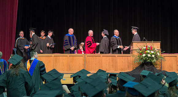 Elder W. Craig Zwick and President Kim B. Clark award diploma covers to graduates in the College of Business and Communication.