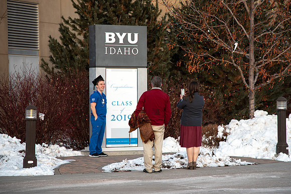 Parents taking a photo of their BYU-Idaho graduate next to sign that says Class of 2019.