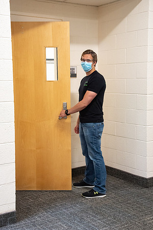 Examples of students staying safe and healthy during the COVID-19 pandemic by social distancing, following pathway arrows, and wearing face masks.