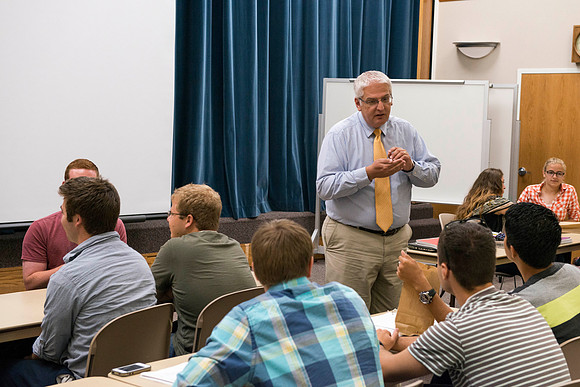 Brother Adamson talks to his students about the hands-on activity they are doing during class.