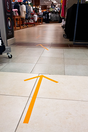 Stickers in the Book Store showing which way to walk down the hallways. The stickers are to direct foot traffic through buildings to try to help fight the virus, COVID-19, on campus.
