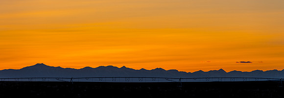 Farm irrigation sprinkler and sunset over the mountains west of Rexburg, Idaho.