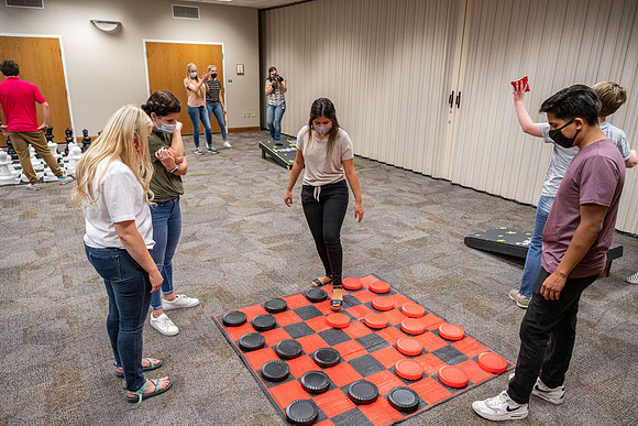 Students socialize and play games together while taking necessary safety precautions.