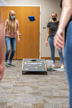 Students socialize and play games together while taking necessary safety precautions.