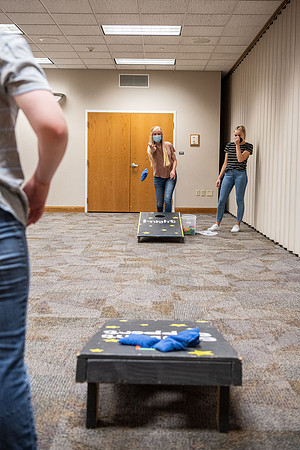Students socialize and play games together while taking necessary safety precautions.