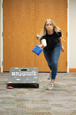 Examples of students staying safe and healthy during the COVID-19 pandemic by social distancing, following pathway arrows, and wearing face masks during activities.