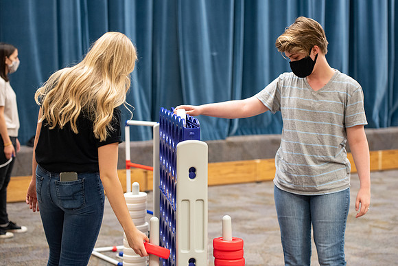 Examples of students staying safe and healthy during the COVID-19 pandemic by social distancing, following pathway arrows, and wearing face masks during activities.