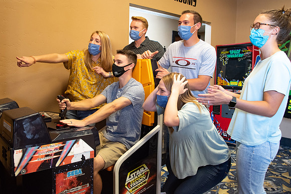 Students at a local movie theater wearing face masks, playing video games.