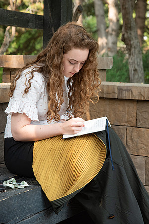 Student writing in her journal in the gardens on campus.