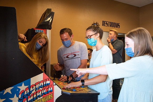 Students at a local movie theater wearing face masks, playing video games.