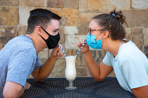 Students off campus wearing face masks and drinking a milkshake.