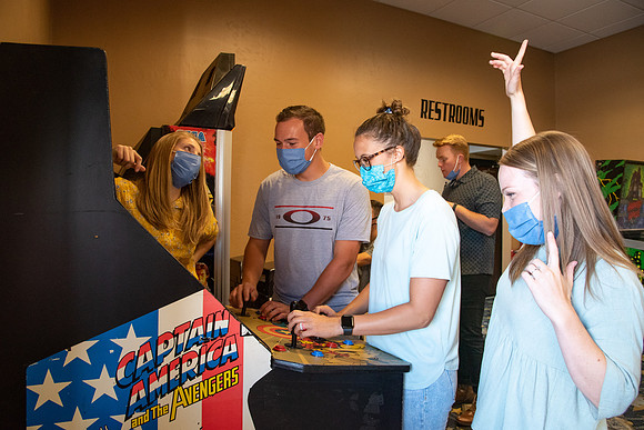 Students at a local movie theater wearing face masks, playing video games.