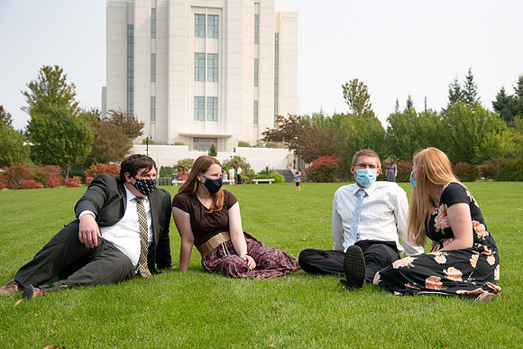 Students sitting at the temple, wearing face masks, after church.