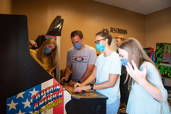 Students at a local movie theater wearing face masks, playing video games.