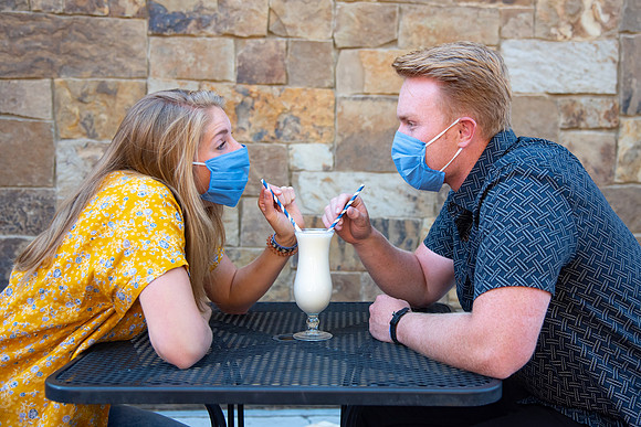 Students off campus wearing face masks and drinking a milkshake.