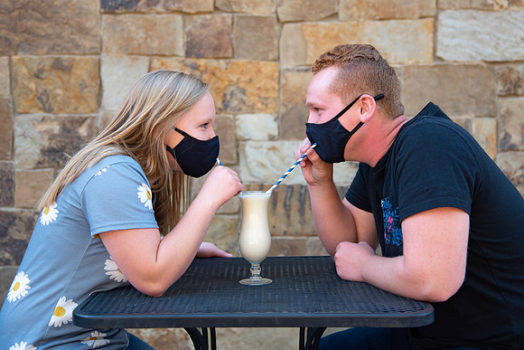 Students off campus wearing face masks and drinking a milkshake.