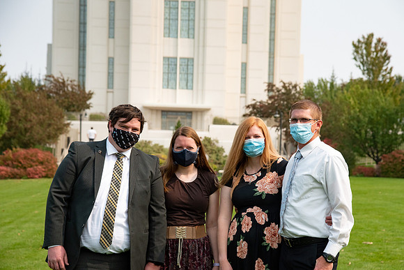 Students sitting at the temple, wearing face masks, after church.