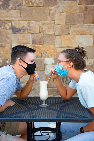 Students off campus wearing face masks and drinking a milkshake.