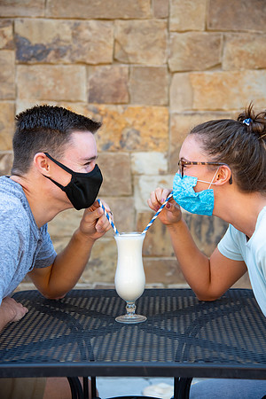 Students off campus wearing face masks and drinking a milkshake.