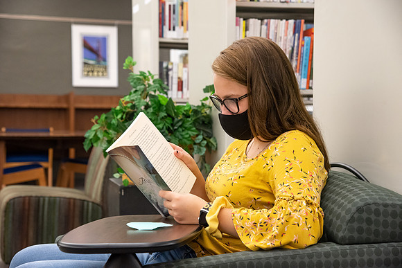 A student wearing a face mask studying in the library.