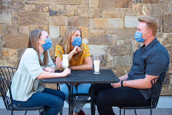 Students off campus wearing face masks and drinking a milkshake.