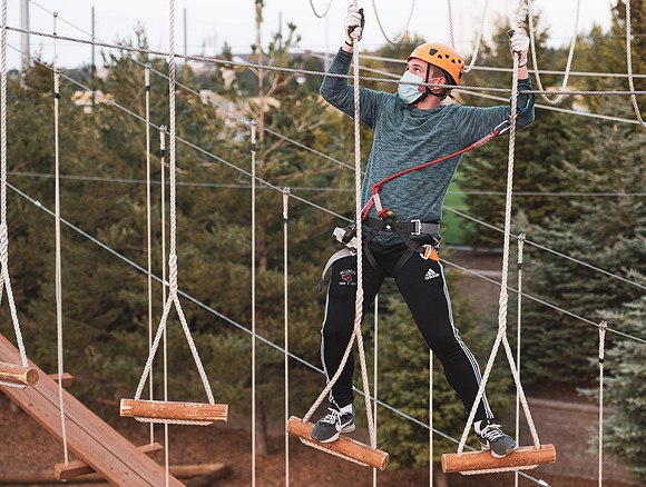 Students navigate the BYU-Idaho ropes course while taking social distancing precautions and wearing masks.